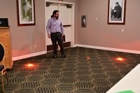 A man performs a demonstration with orange lights placed on the floor.