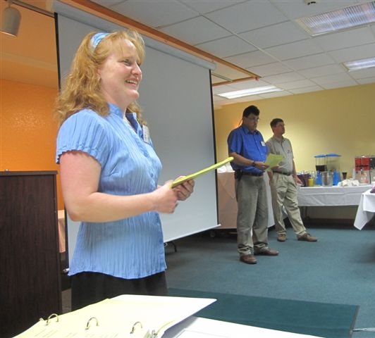 A woman speaking with a notepad in her hand.